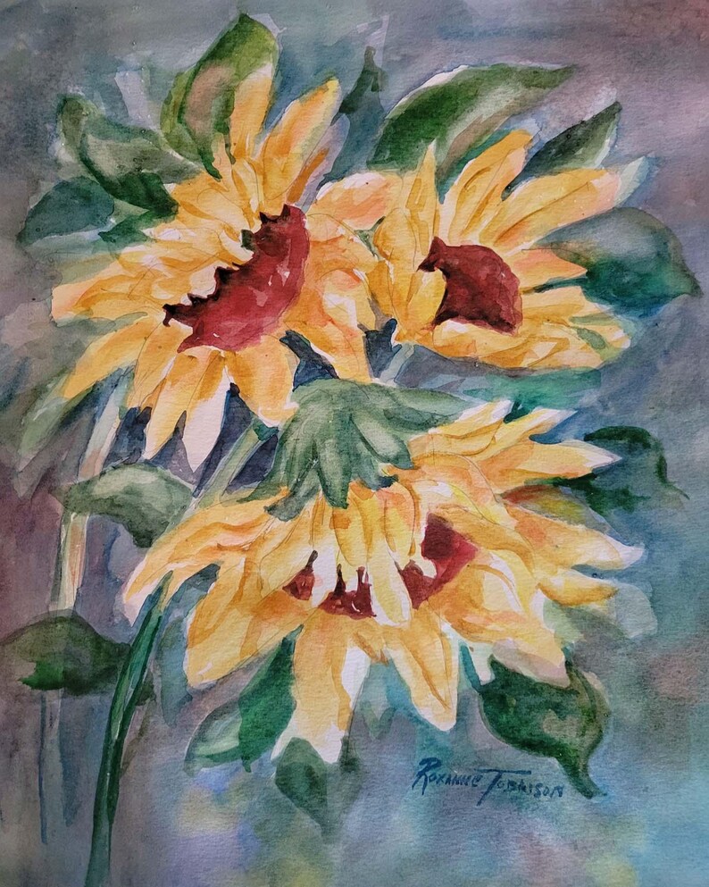 May include: A watercolor painting of three yellow sunflowers with red centers. The sunflowers are painted in a loose style with visible brushstrokes. The background is a light blue-gray color. The artist's signature is visible in the lower right corner.
