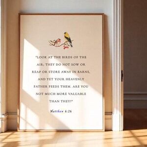Op de afbeelding: Een ingelijste print met een citaat uit Mattheüs 6:26, met een aquarel illustratie van twee vogels op een tak. De tekst is zwart op een crèmekleurige achtergrond, omlijst door lichtbruin.