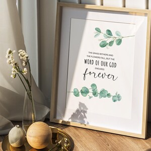 May include: A framed print with a watercolor illustration of green leaves and the text "THE GRASS WITHERS AND THE FLOWERS FALL, BUT THE WORD OF OUR GOD ENDURES forever".