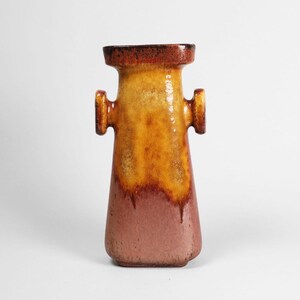 Pode incluir: Um vaso de cerâmica com uma forma única e um esquema de cores gradiente. A parte superior é marrom escuro, passando para amarelo e laranja no meio e terminando com um rosa empoeirado na base. Possui duas pequenas alças.