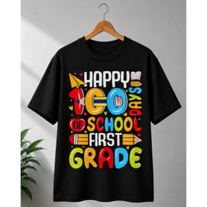 Può includere: Una t-shirt nera a maniche corte con una grafica colorata e la scritta "HAPPY 100 DAYS OF SCHOOL FIRST GRADE". Il design include un aeroplanino di carta giallo, una mela rossa, una matita che forma il numero 100 e un'icona di libro aperto.