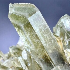 May include: Close-up of a cluster of green and clear quartz crystals. The crystals are translucent and have a rough, natural texture.