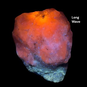 May include: A glowing, rough-textured mineral specimen with a vibrant orange hue, illuminated against a black background. The text "Long Wave" is visible. The lower portion of the rock has a blue-green color.