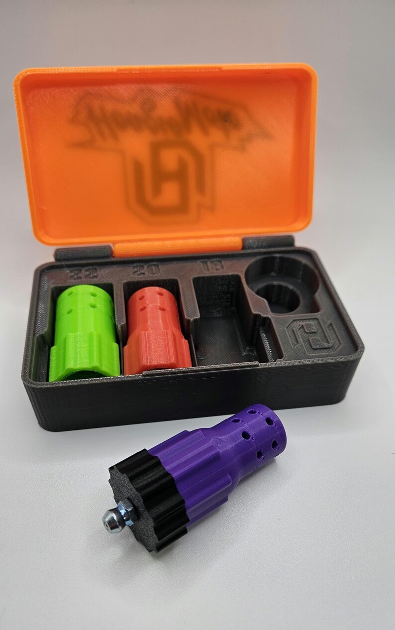 May include: An open orange and black case containing three colored cylindrical objects and a black object. A detached purple and black object with a bolt is in front of the case. The case lid has the text "Hoodlums" and a logo.