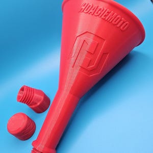 Puede incluir: Embudo de plástico rojo con el texto "HOAGIE MOTO" y un logotipo. Incluye dos tapones de plástico rojo. El embudo tiene una boquilla larga y cónica y una abertura ancha. Las tapas son cilíndricas. Sobre un fondo azul.