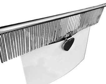 May include: A silver comb with a heart-shaped clip attached to a clear acrylic sign. The comb has a row of fine teeth and is designed for grooming.