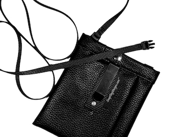 May include: A black leather crossbody bag with a zipper closure and an adjustable strap. The bag has a small pocket on the front with the text "SimplyDogDesigns.com" printed on it.
