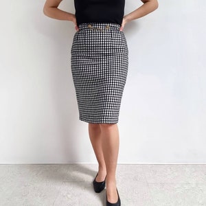 Może przedstawiać: Czarno-biała spódnica ołówkowa w kratkę gingham z ozdobnym złotym łańcuszkiem w talii.