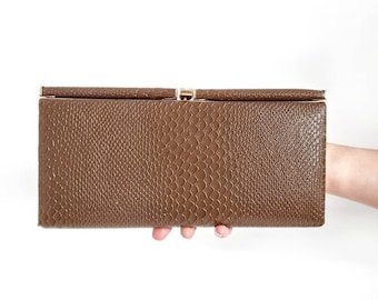 May include: A brown faux leather clutch with a gold clasp.
