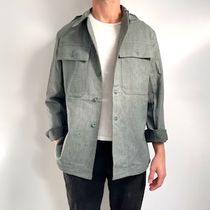 Pode incluir: Uma camisa verde de manga comprida com dois bolsos grandes e fecho de botões.