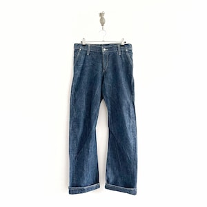 May include: A pair of dark blue denim jeans with a cuffed hem. The jeans are hanging on a hanger.