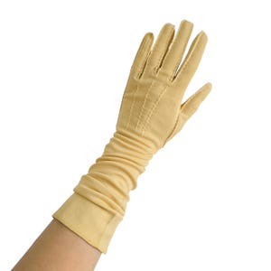 Peut inclure: Un seul gant jaune pâle avec une longue manche froncée. Le gant a un design classique avec des détails cousus sur les doigts et un poignet lisse. Le tissu semble être un matériau léger.