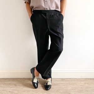 Puede incluir: Una persona con pantalones negros y zapatos negros y blancos con borlas.