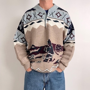 Może przedstawiać: Sweter w stylu vintage z kołnierzem i zapięciem na guziki. Sweter posiada krajobrazowy wzór w odcieniach brązu, niebieskiego, kremowego i bordowego. Rękawy mają wzór o fakturze, a ramiona geometryczny wzór.