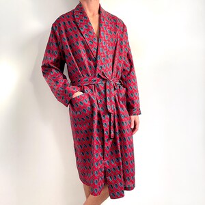 May include: A red paisley patterned robe with a long sleeve and a sash tie.