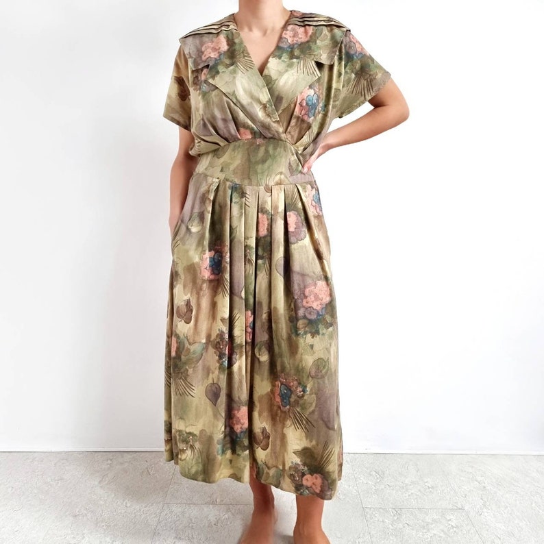 May include: A green and brown floral print dress with a V-neck and short sleeves. The dress has a fitted bodice and a flowing skirt.