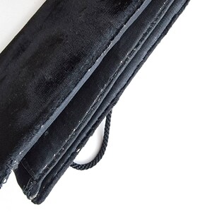 May include: A black velvet clutch bag with a drawstring closure and a black fabric lining.