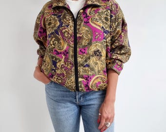 May include: A vintage-style jacket with a colorful, abstract print featuring gold, purple, and black accents. The jacket has a zipper closure and long sleeves.
