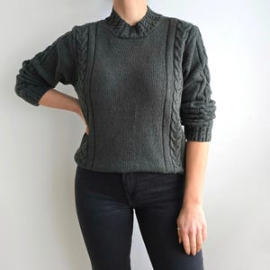 Peut inclure: Un pull en tricot vert foncé à col montant et détails en tricot torsadé. Le pull a une coupe décontractée et est fait d'un matériau doux et confortable.