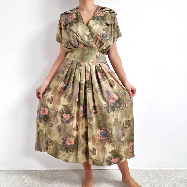 May include: A vintage floral print dress with a pleated skirt and a collared neckline. The dress is made of a soft, flowing fabric and has a relaxed fit.