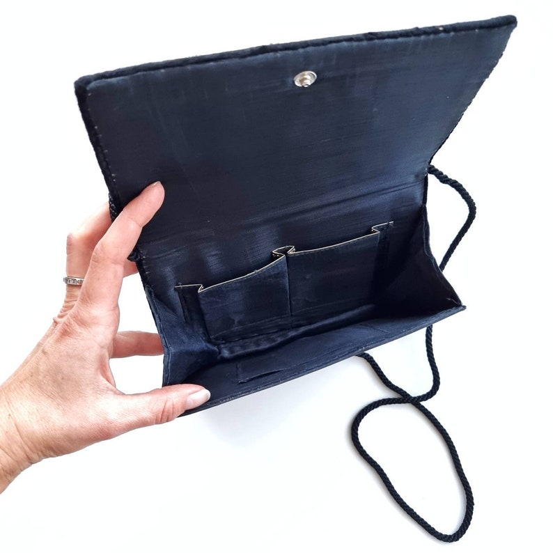 May include: A black velvet evening bag with a long black strap and three interior pockets.