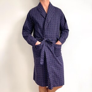 Peut inclure: Peignoir bleu marine avec un motif géométrique blanc. Le peignoir a des manches longues, un col châle, des poches et une ceinture assortie. Le peignoir, en tissu doux, arrive au niveau des genoux.