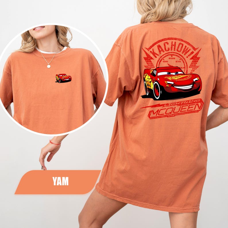 May include: An orange t-shirt featuring a small graphic of the red race car Lightning McQueen on the front left chest. The back displays a large graphic of Lightning McQueen with the text KACHOW! and LIGHTNING MCQUEEN in red ink.