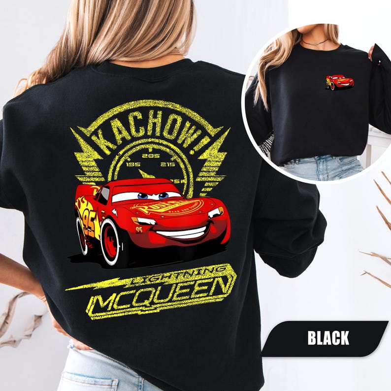May include: A black sweatshirt featuring a large graphic on the back of a red race car with the text KACHOW and LIGHTNING MCQUEEN in yellow. A smaller version of the same red race car is printed on the front left chest area of the garment.