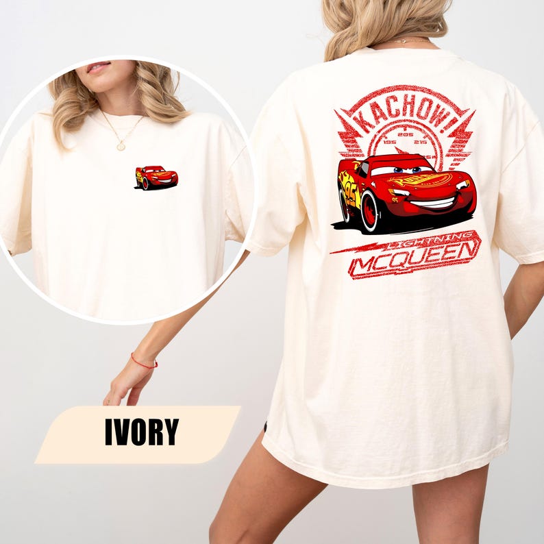 May include: An ivory t-shirt featuring a small graphic of a red race car on the front left chest. The back displays a large red graphic of the same race car with the text KACHOW! and LIGHTNING MCQUEEN printed in a distressed red font style.