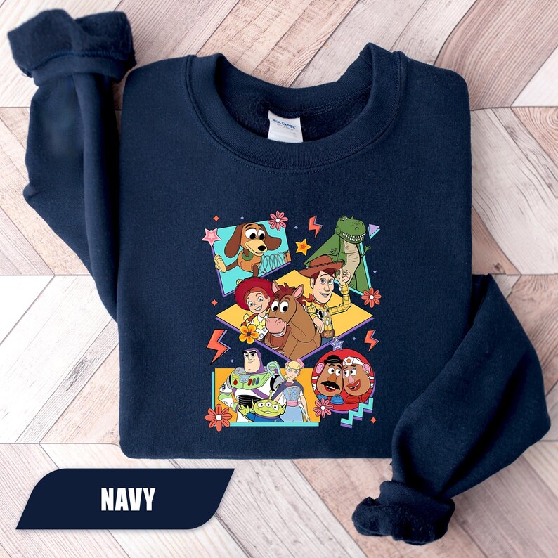 Puede incluir: Sudadera azul marino con un gr&aacute;fico colorido de personajes de dibujos animados. El dise&ntilde;o incluye un perro, un dinosaurio, un vaquero y otros personajes. La palabra "NAVY" est&aacute; impresa en la parte inferior.