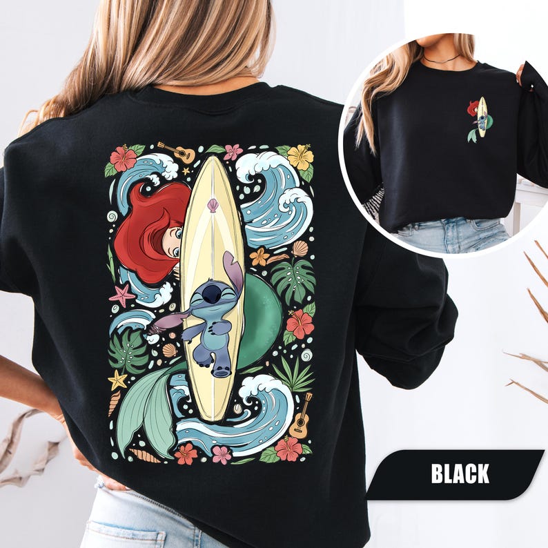 May include: A black sweatshirt featuring a large graphic on the back of Stitch and Ariel from The Little Mermaid with a surfboard, tropical flowers, waves, and a ukulele. A smaller version of the same graphic is printed on the front left chest.