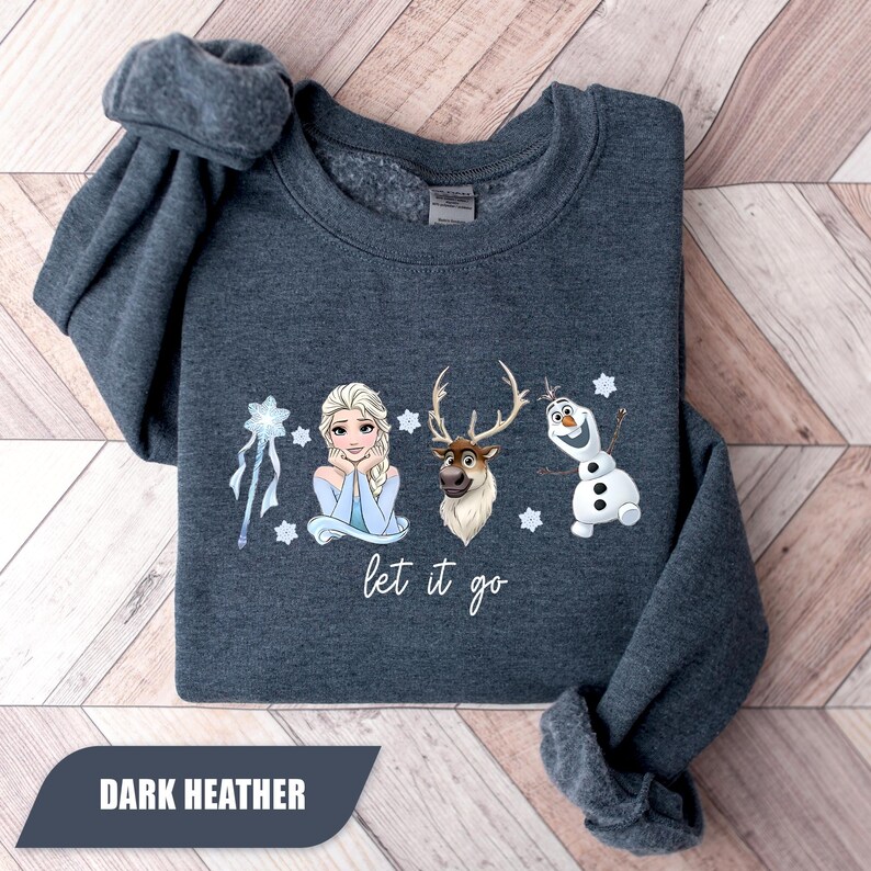 May include: Dark heather gray sweatshirt featuring Elsa, Sven, and Olaf from Frozen. The phrase "let it go" is written below the characters. The sweatshirt has rolled sleeves and the words "DARK HEATHER" are printed on a dark rectangle.