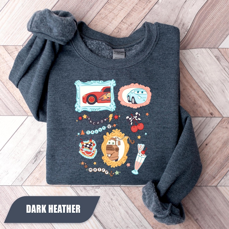 Puede incluir: Una sudadera de cuello redondo en gris jaspeado oscuro con un estampado gr&aacute;fico de personajes de la pel&iacute;cula Cars. El dise&ntilde;o incluye ilustraciones enmarcadas de Rayo McQueen, Sally y Mate, junto a iconos como un batido, cerezas y texto.
