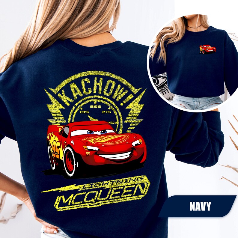 May include: A navy blue sweatshirt featuring a large graphic on the back of the red race car Lightning McQueen with the text KACHOW! and LIGHTNING MCQUEEN in yellow. A smaller version of the red race car is printed on the front left chest area.