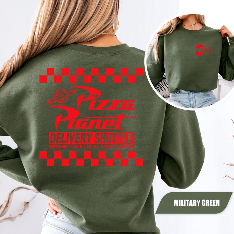 May include: A military green crewneck sweatshirt featuring a red graphic on the back with a checkered border, the text Pizza Planet, and the words DELIVERY SHUTTLE SERVING YOUR LOCAL STAR CLUSTER. A smaller matching red logo is on the front chest.