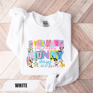 May include: White sweatshirt with the text "I was made for happy sunny days" in colorful letters. The design includes cartoon characters like Mickey Mouse, Donald Duck, and Pluto. The word "WHITE" is at the bottom.