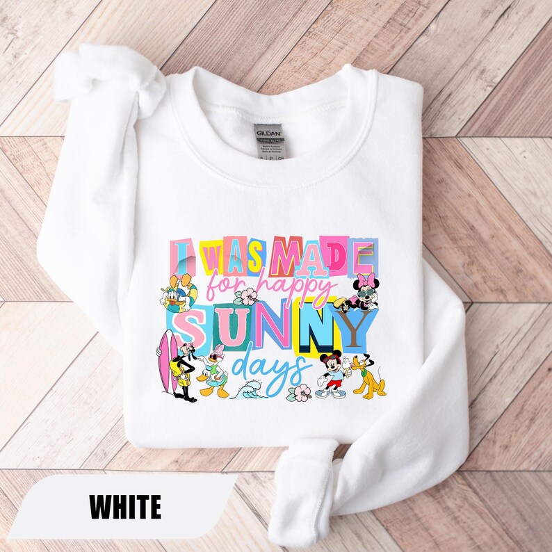 May include: White sweatshirt with the text "I was made for happy sunny days" in colorful letters. The design includes cartoon characters like Mickey Mouse, Donald Duck, and Pluto. The word "WHITE" is at the bottom.