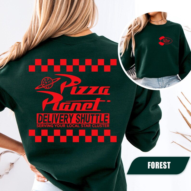May include: A forest green crewneck sweatshirt featuring a red graphic on the back with a checkered border, the text Pizza Planet, Delivery Shuttle, and Serving Your Local Star Cluster. A smaller red Pizza Planet logo is on the front left chest.