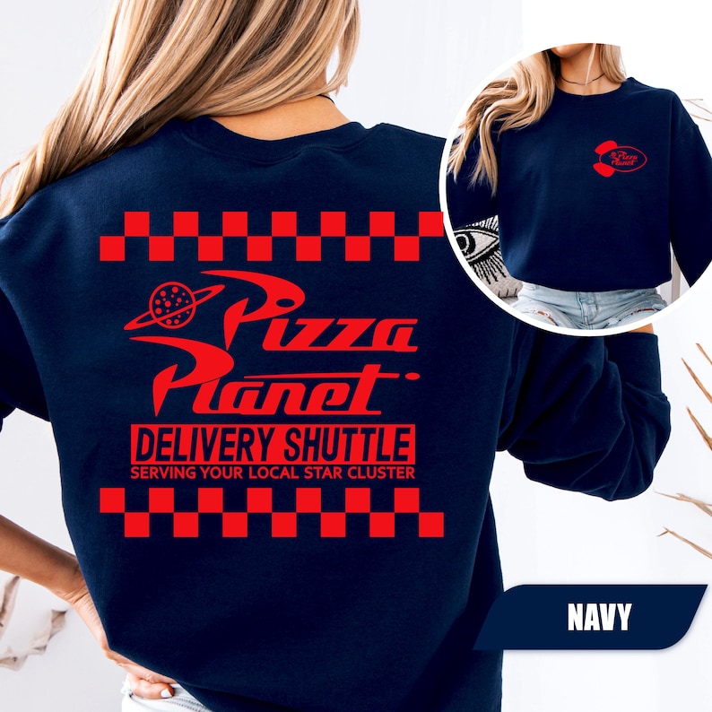 May include: A navy blue crewneck sweatshirt featuring a red graphic on the back with a checkered border, the text Pizza Planet, Delivery Shuttle, and Serving Your Local Star Cluster. A smaller red Pizza Planet logo is printed on the front left chest.