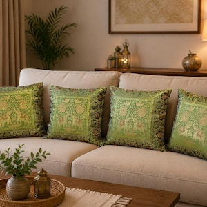 May include: Four square throw pillows featuring a vibrant green and gold woven pattern. The design displays a central light green square panel with intricate elephant and floral motifs, framed by a dark green border with detailed botanical patterns.