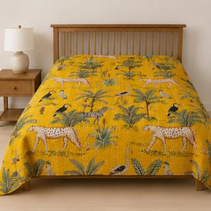 Pode incluir: Uma colcha amarelo-mostarda com um padrão repetitivo de guepardos, zebras, tucanos e grous intercalados com palmeiras verdes e folhagem tropical. O tecido apresenta linhas de costura verticais visíveis em toda a sua superfície.