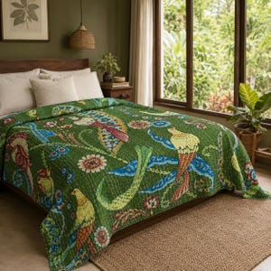 Op de afbeelding: Een groene doorgestikte sprei met een herhalend patroon van kleurrijke vogels, bloemmotieven en krullende ranken. De stof is voorzien van gedetailleerd stikwerk en heeft accenten in geel, blauw en rood op een groene ondergrond.