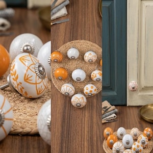May include: A collection of round ceramic cabinet knobs featuring various patterns in orange and white. Each knob has a silver-toned metal base and center detail. The designs include floral motifs, stripes, and polka dots, displayed in groups.