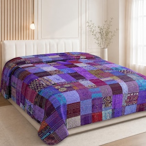 Peut inclure: Un couvre-lit rectangulaire composé d'un assemblage de carrés de tissu dans des tons de violet, pourpre et bleu. Le textile présente des surpiqûres kantha complexes, avec certaines sections ornées de motifs floraux et géométriques.