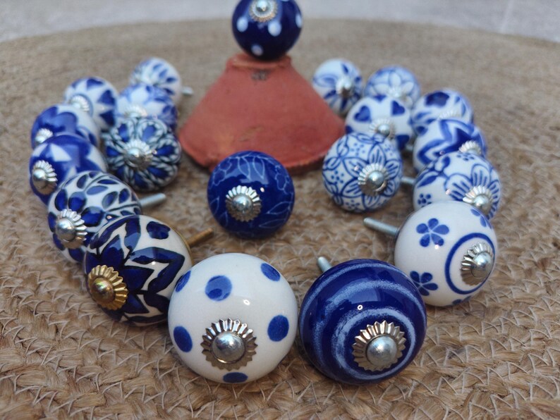 May include: A white ceramic mug with a black handle and the text "But First, Coffee" in a black, handwritten-style font. The mug is on a white surface.