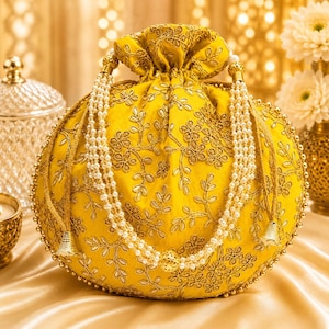 Könnte beinhalten: Ein leuchtend gelber Beutel mit Kordelzug und aufwendiger goldener Blumenstickerei. Die Tasche ist mit zwei langen, mehrsträngigen Perlenhenkeln akzentuiert, die vorne herabhängen und mit kleinen, kegelförmigen goldenen Metallquasten versehen sind.