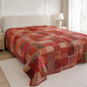 Peut inclure: Un couvre-lit en patchwork rectangulaire composé de carrés de tissu rouges, orange et roses aux motifs floraux et géométriques variés. Le couvre-lit présente des lignes de couture visibles sur toute la surface, créant un aspect texturé.