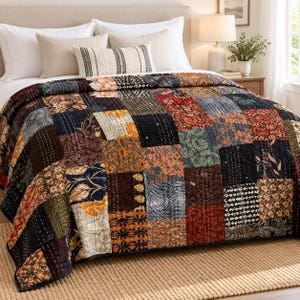 Puede incluir: Una colcha de patchwork que presenta una variedad de paneles de tela rectangulares en tonos azul marino, rojo intenso, amarillo mostaza y verde bosque. La colcha muestra diversos patrones florales, botánicos y geométricos con costuras kantha blancas.