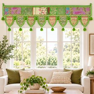 May include: A window valance featuring a patchwork design of green, pink, and cream fabric panels with intricate floral and paisley patterns. The valance has a straight top edge and a scalloped bottom border adorned with green fabric tassels.