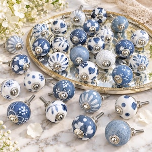 Set van 10 keramische kastknoppen, diverse grijs-witte bloemmotieven, decoratieve handgrepen voor dressoirs en keukenkasten.
